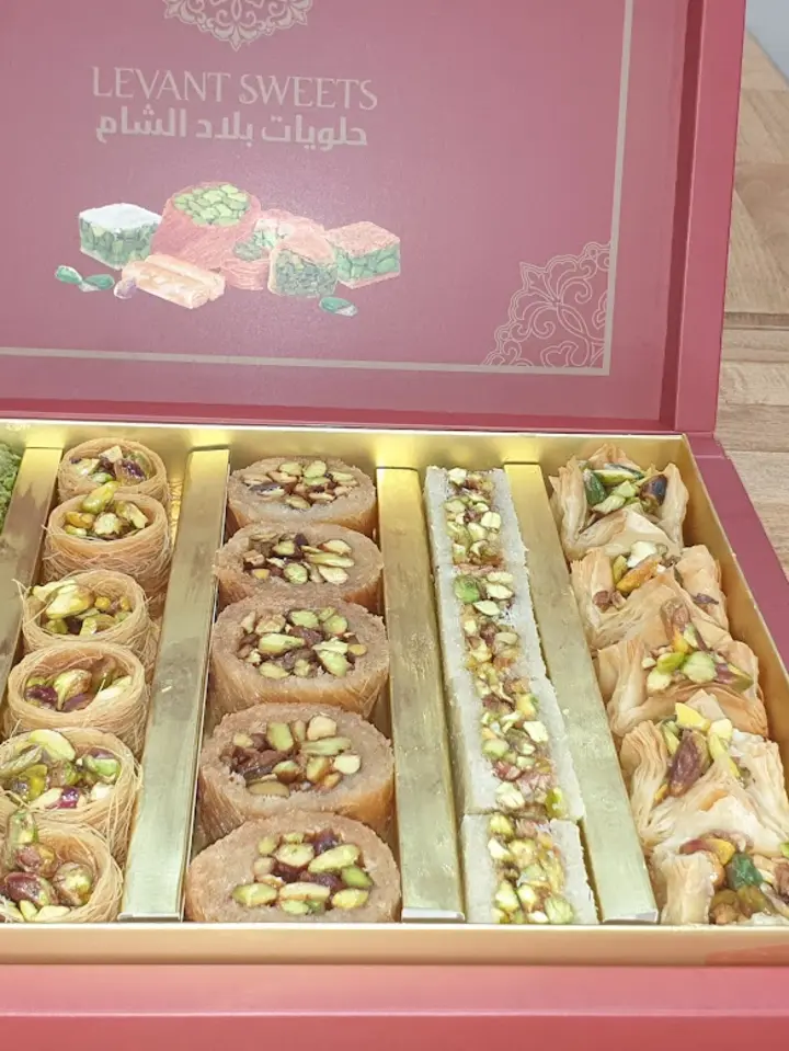 An open Levant Sweets gift box of assorted baklava and pistachio rolls