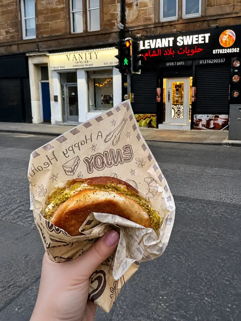 Kunafa held in hand outside the Levant Sweets shopfront on Dalry Road at dusk